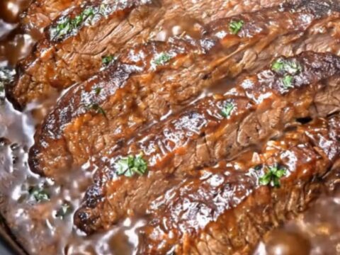 A close-up shot of a fork lifting an ultra-tender, glistening slice of slow cooker BBQ brisket.