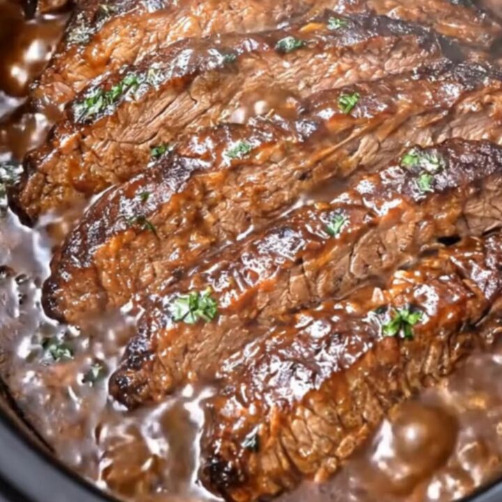 A close-up shot of a fork lifting an ultra-tender, glistening slice of slow cooker BBQ brisket.