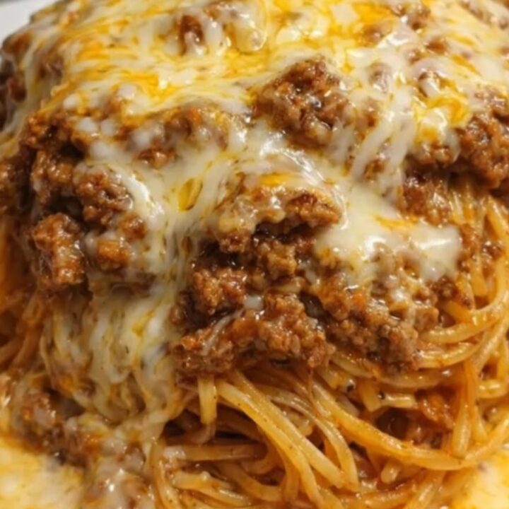 A tall, steaming mound of saucy garlic spaghetti topped with seasoned ground beef and a bubbly