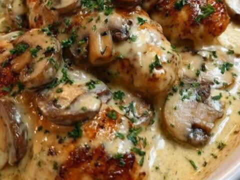 A white oval dish containing juicy seared chicken tenders smothered in a velvety garlic mushroom cream sauce and garnished