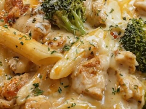 A warm skillet of baked chicken penne and broccoli covered in golden, bubbling melted mozzarella cheese.