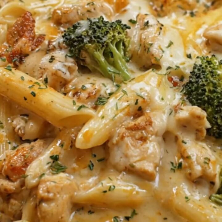 A warm skillet of baked chicken penne and broccoli covered in golden, bubbling melted mozzarella cheese.