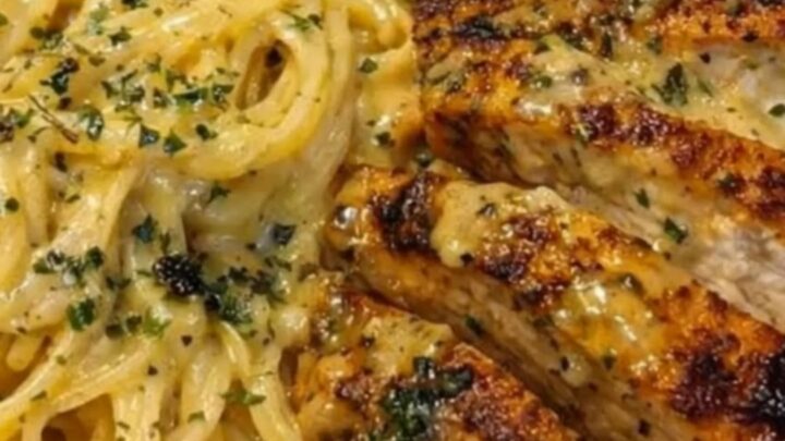 Sliced golden-brown seared chicken breast arranged next to a mound of glossy, herb-speckled spaghetti in a white bowl.