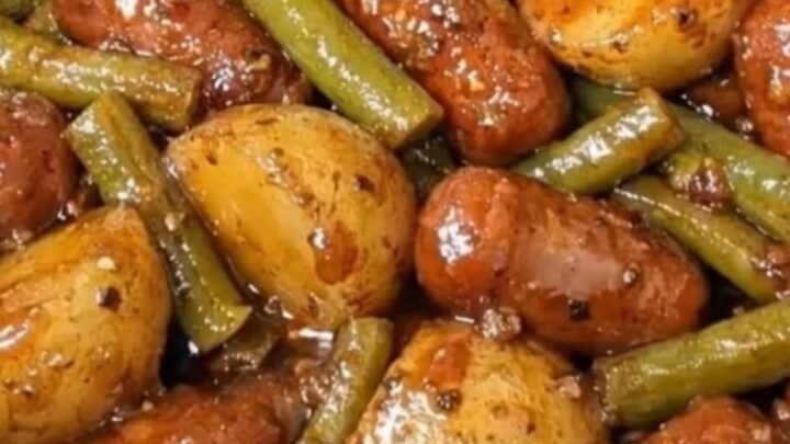A slow cooker filled with glistening glazed cocktail wieners, tender quartered red potatoes, and green beans.
