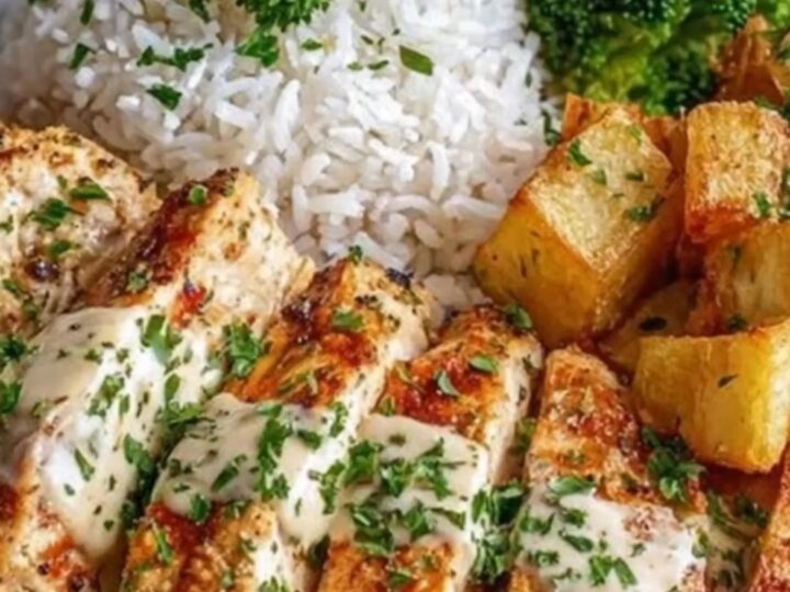 A beautifully plated meal featuring sliced golden seared chicken breast, crispy roasted potatoes, steamed broccoli, and rice