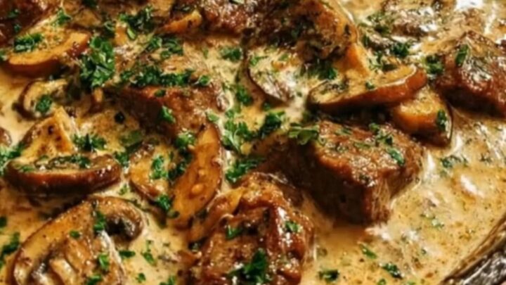 A rustic cast iron skillet filled with creamy beef and mushroom gravy, garnished with fresh chopped parsley.