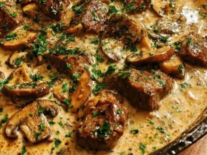A rustic cast iron skillet filled with creamy beef and mushroom gravy, garnished with fresh chopped parsley.