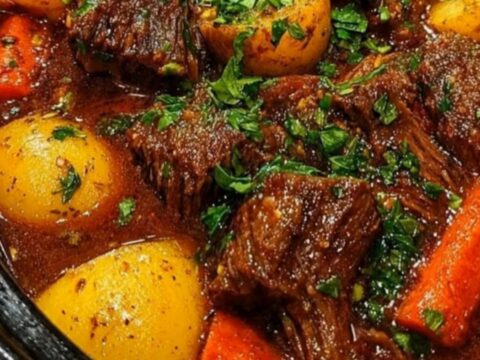 A close-up of tender slow cooker beef stew in a black cooker, topped with fresh green parsley.