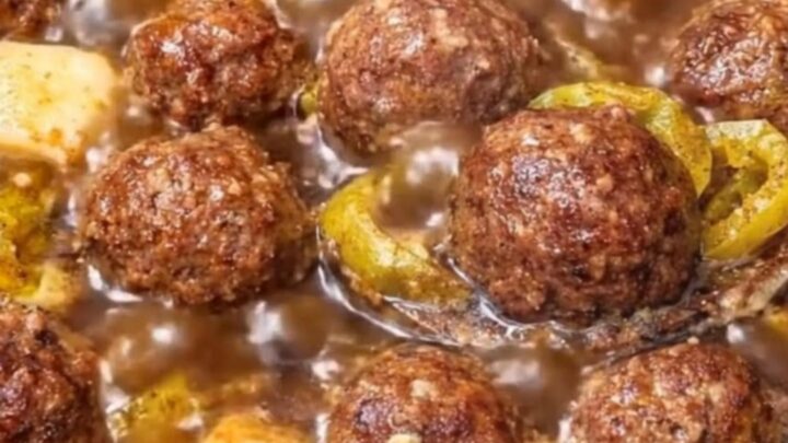 A close-up of a glistening Mississippi meatball dripping with rich au jus gravy and melted butter on a spoon.