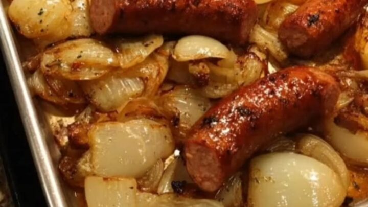 Slices of juicy roasted sausage mixed with sweet, golden-brown caramelized onions in a metal baking tray.
