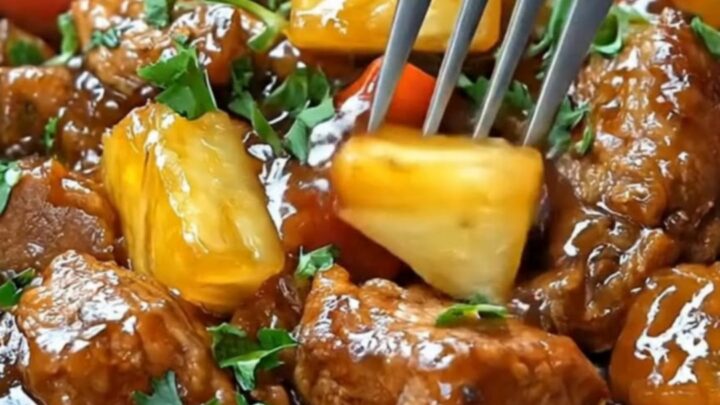 A slow cooker bowl filled with glossy, tender hoisin pork chunks, vibrant bell peppers, sweet pineapple