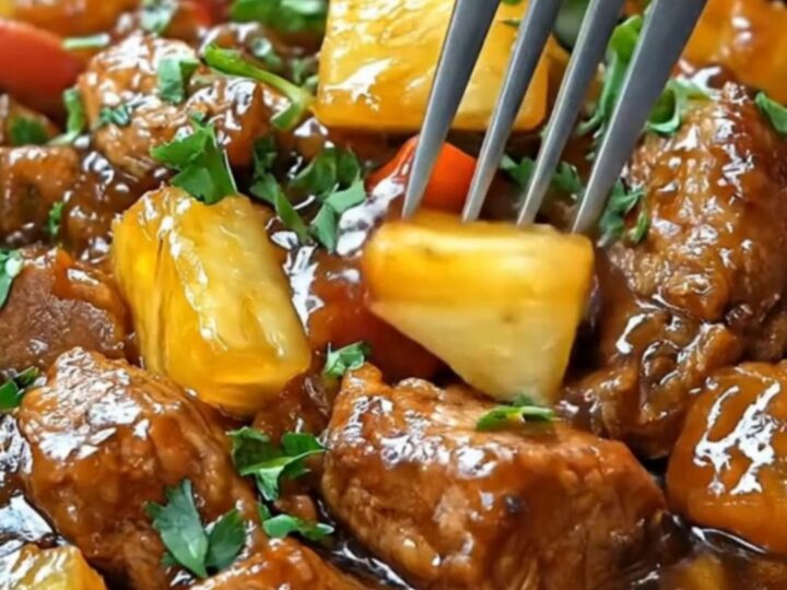 A slow cooker bowl filled with glossy, tender hoisin pork chunks, vibrant bell peppers, sweet pineapple