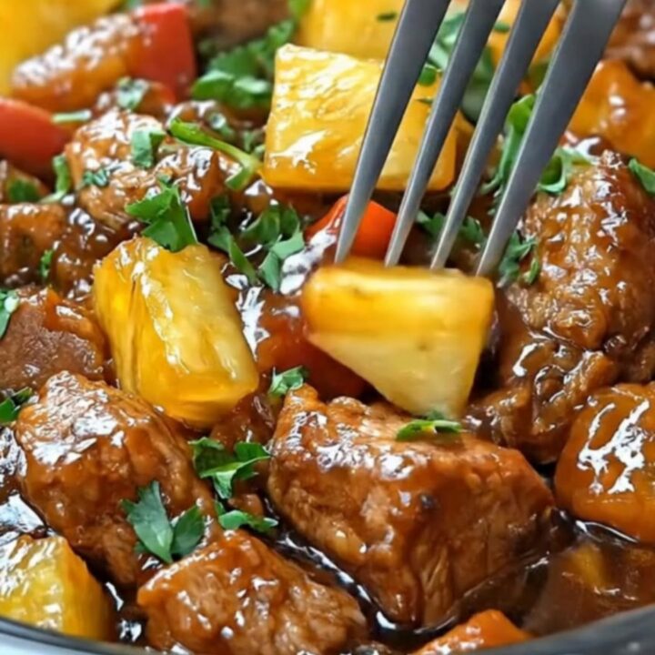 A slow cooker bowl filled with glossy, tender hoisin pork chunks, vibrant bell peppers, sweet pineapple