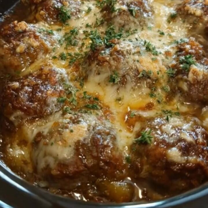 Slow cooker filled with savory French onion beef meatballs topped with a blanket of melted