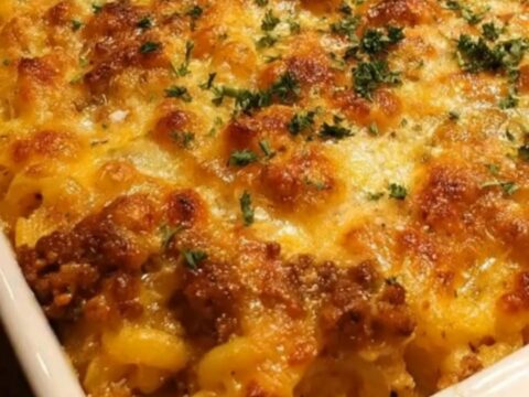 A large slice of cheesy mac and cheese meatloaf bake being lifted with a spatula, showing gooey melted cheese.