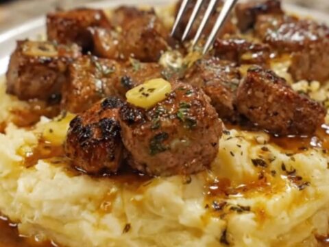 Tender garlic butter steak bites arranged over a bed of fluffy, creamy parmesan mashed potatoes.