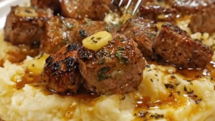 Tender garlic butter steak bites arranged over a bed of fluffy, creamy parmesan mashed potatoes.