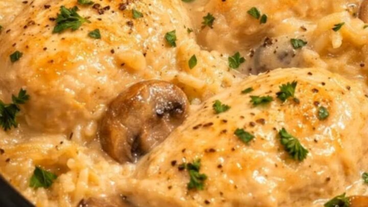 A fork pulling apart tender chicken nestled in a creamy mushroom rice bed inside a slow cooker.