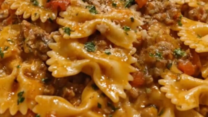 A steaming forkful of creamy bowtie pasta coated in a rich beef and tomato sauce.