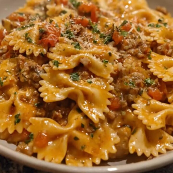 A steaming forkful of creamy bowtie pasta coated in a rich beef and tomato sauce.