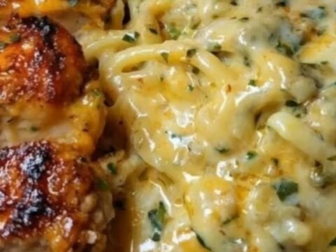 A close-up shot of creamy three-cheese spaghetti topped with perfectly sliced seared Cajun chicken breasts and fresh parsley.