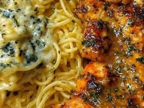 A plate of creamy parmesan spaghetti topped with sliced golden-brown garlic butter chicken cutlets.