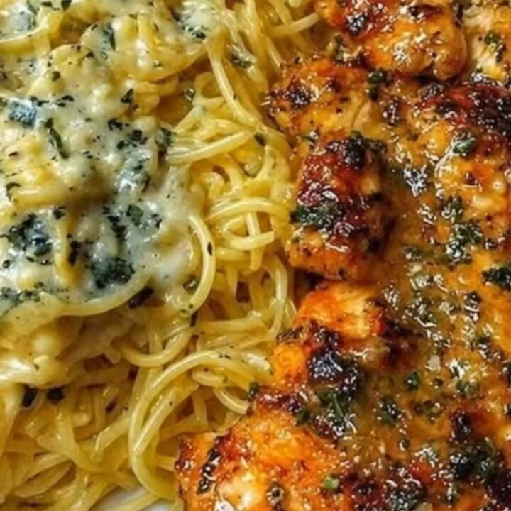 A plate of creamy parmesan spaghetti topped with sliced golden-brown garlic butter chicken cutlets.