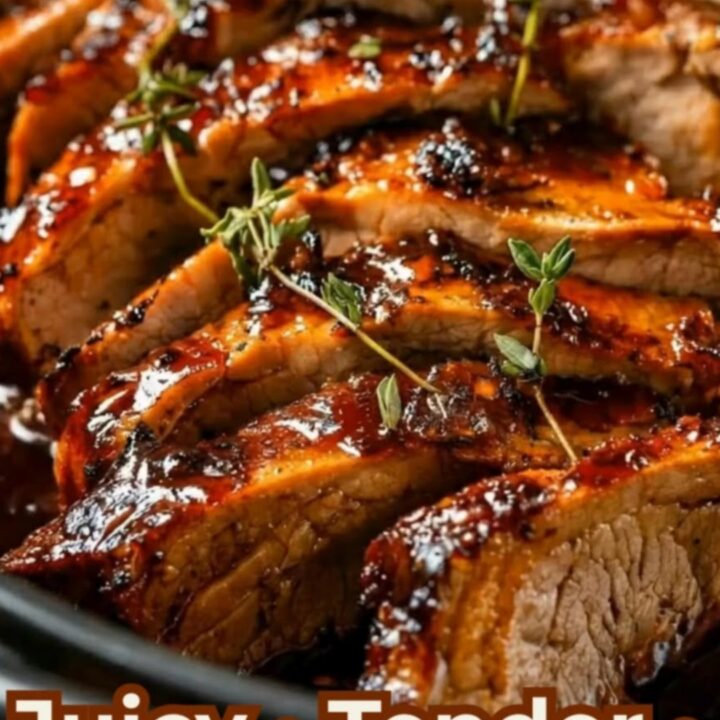 Sliced brown sugar garlic pork roast in a black oval pan garnished with fresh thyme