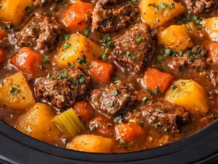 A steaming ladle scooping tender chunks of beef and golden potatoes from a rich, thick brown gravy.