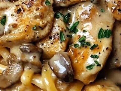 A close-up of glossy Cajun chicken linguine with mushrooms and fresh parsley garnish
