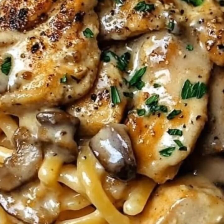A close-up of glossy Cajun chicken linguine with mushrooms and fresh parsley garnish