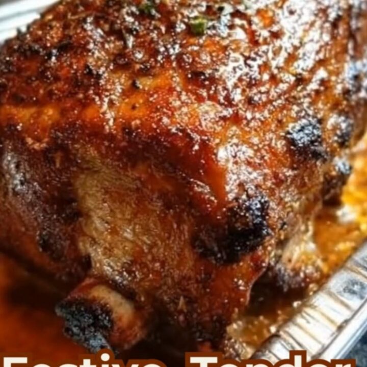 A glistening, herb-crusted glazed turkey roast resting in a foil pan surrounded by savory drippings.