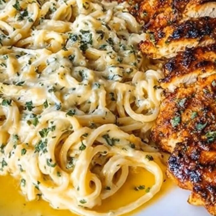Sliced golden parmesan-crusted chicken with melted mozzarella next to a nest of creamy garlic spaghetti.