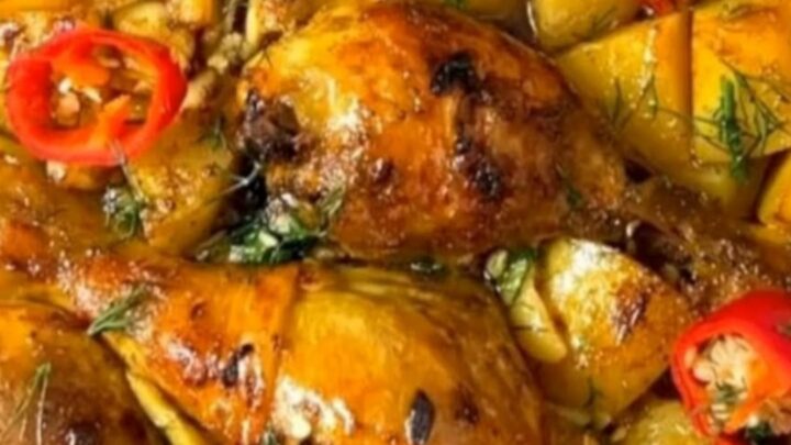 A ceramic baking dish filled with golden, crispy garlic roasted chicken drumsticks and tender potato wedges