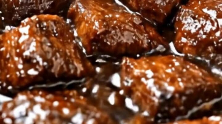 A slow cooker filled with tender, glistening beef tips covered in a rich, dark brown gravy.