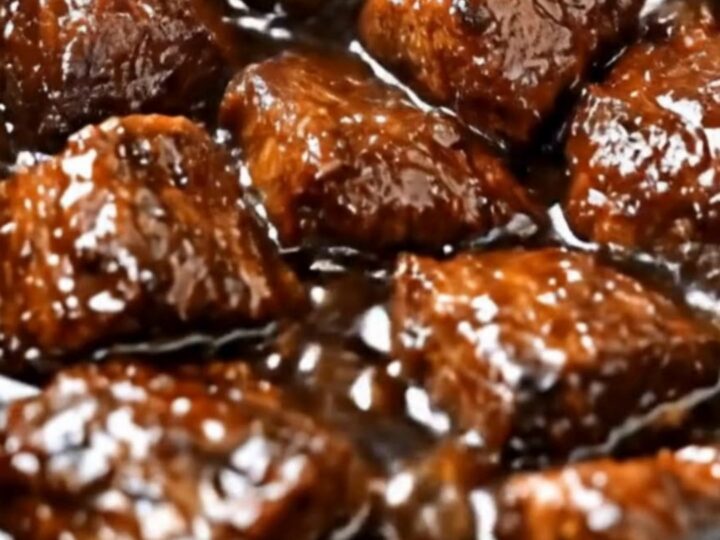 A slow cooker filled with tender, glistening beef tips covered in a rich, dark brown gravy.