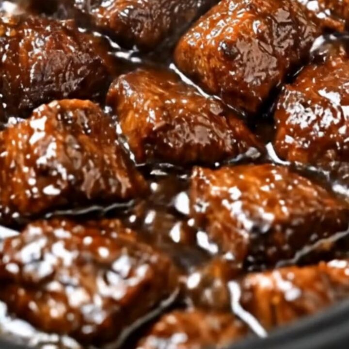 A slow cooker filled with tender, glistening beef tips covered in a rich, dark brown gravy.