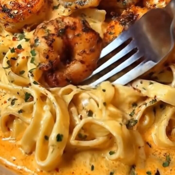 A white bowl filled with creamy Cajun garlic shrimp fettuccine alfredo, garnished with fresh parsley.