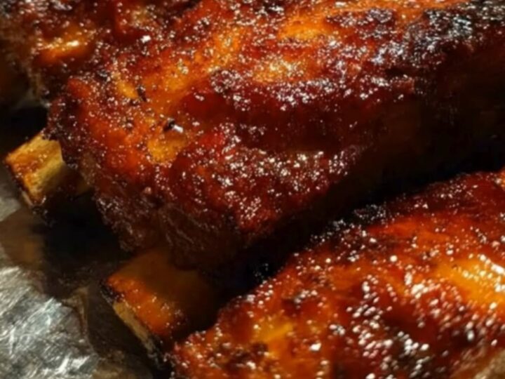 A platter of caramelized, glazed country-style pork ribs glistening with sweet barbecue sauce.