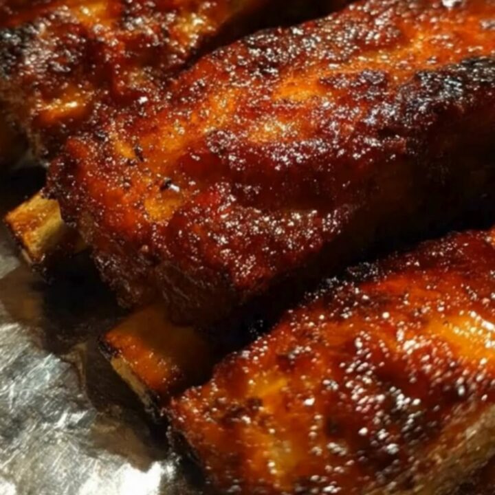A platter of caramelized, glazed country-style pork ribs glistening with sweet barbecue sauce.