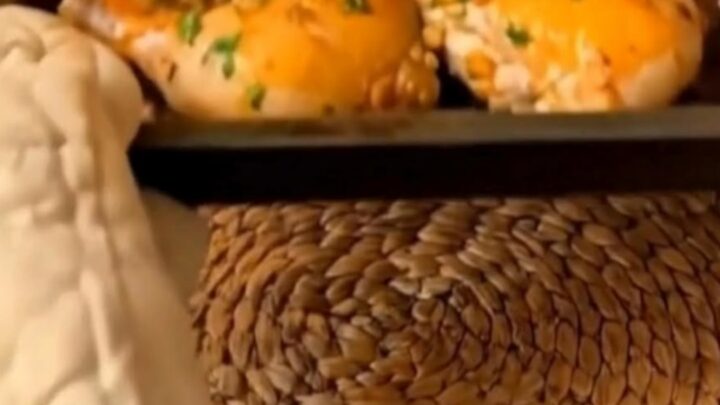 A golden-brown baked chicken thigh glistening with garlic butter and garnished with fresh green parsley.