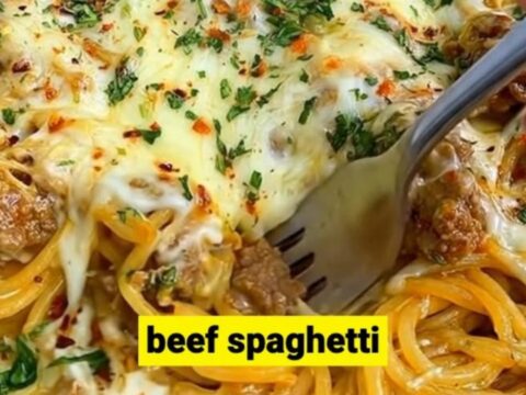 A hot cast-iron skillet filled with creamy Cajun beef spaghetti, topped with a bubbly, golden-brown layer of melted cheese