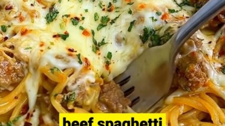A hot cast-iron skillet filled with creamy Cajun beef spaghetti, topped with a bubbly, golden-brown layer of melted cheese