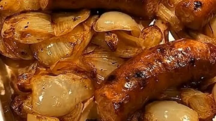 A metal baking sheet filled with browned, juicy roasted sausages and tender