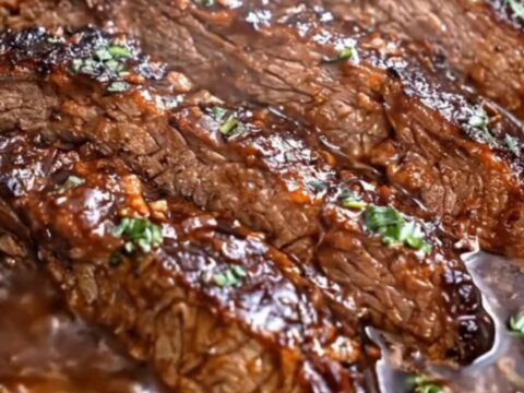 A close-up of tender, glistening slices of brown sugar garlic beef resting in a rich, dark gravy inside a slow cooker
