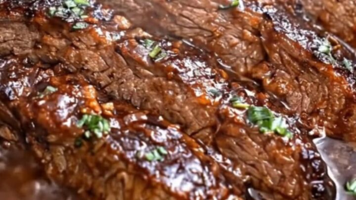 A close-up of tender, glistening slices of brown sugar garlic beef resting in a rich, dark gravy inside a slow cooker
