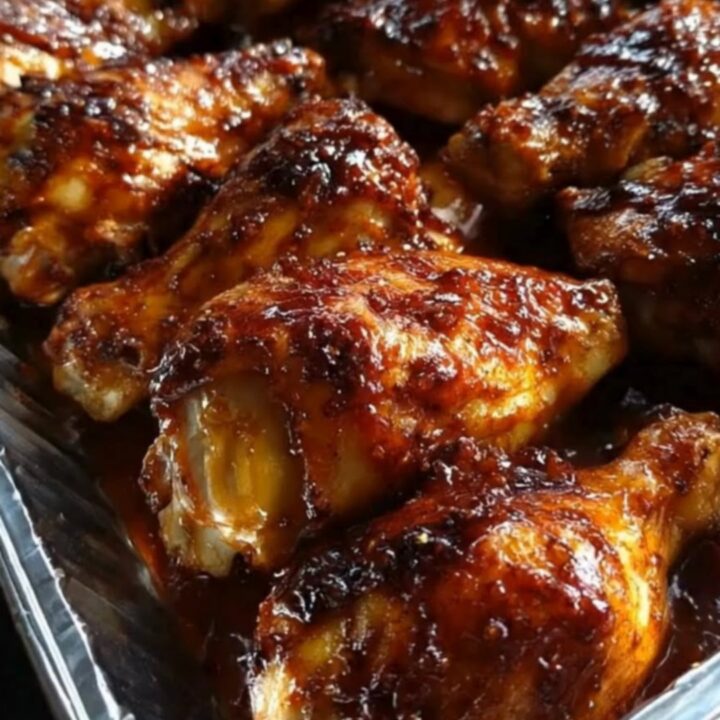 A platter of glistening, sticky honey BBQ chicken drumsticks with a deeply caramelized glaze.