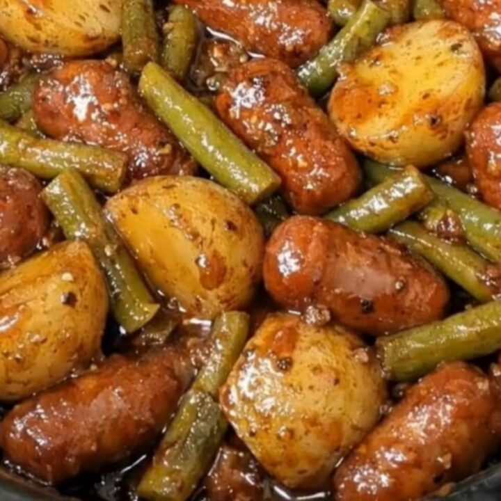 Slow cooker filled with glistening cocktail sausages, tender halved baby potatoes, and green beans in a rich glaze.