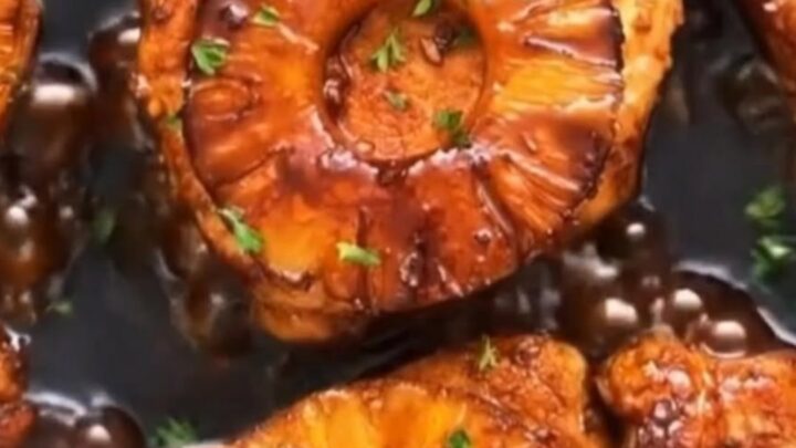 Glistening skillet filled with seared teriyaki pork chops topped with caramelized pineapple slices in a bubbling glaze.
