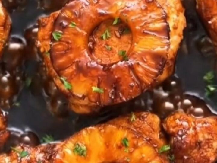 Glistening skillet filled with seared teriyaki pork chops topped with caramelized pineapple slices in a bubbling glaze.
